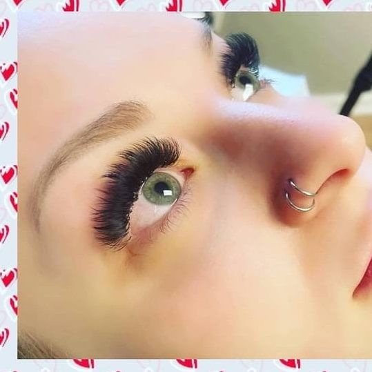 A close up of a woman 's face with long eyelashes and a nose ring.