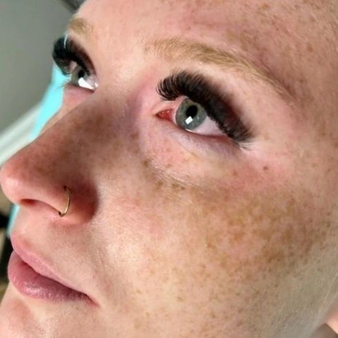 A close up of a woman 's face with long eyelashes and a nose ring.