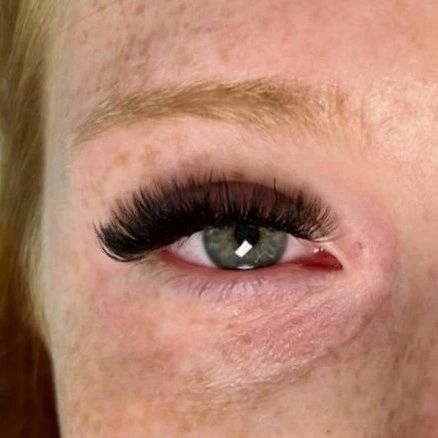 A close up of a woman 's eye with long eyelashes.