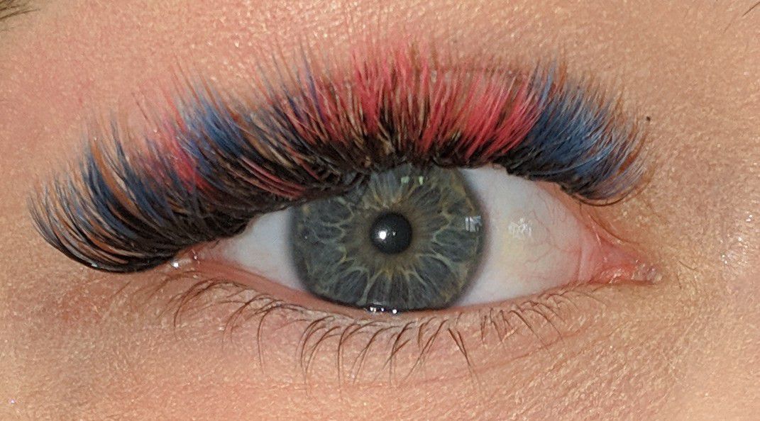 A close up of a woman 's eye with red and blue eyelashes.