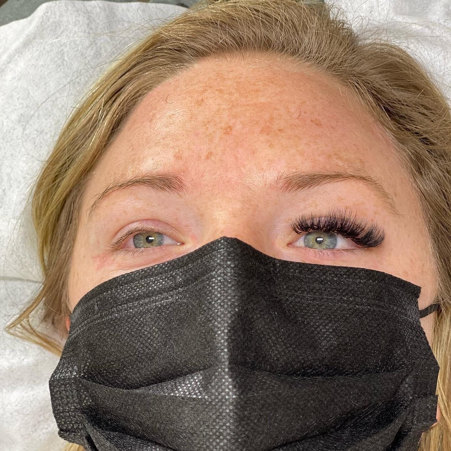 A woman wearing a black face mask with long eyelashes.