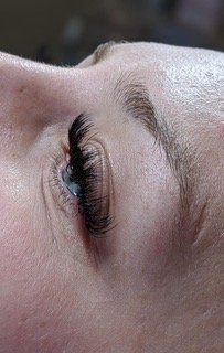 A close up of a woman 's eye with long eyelashes.