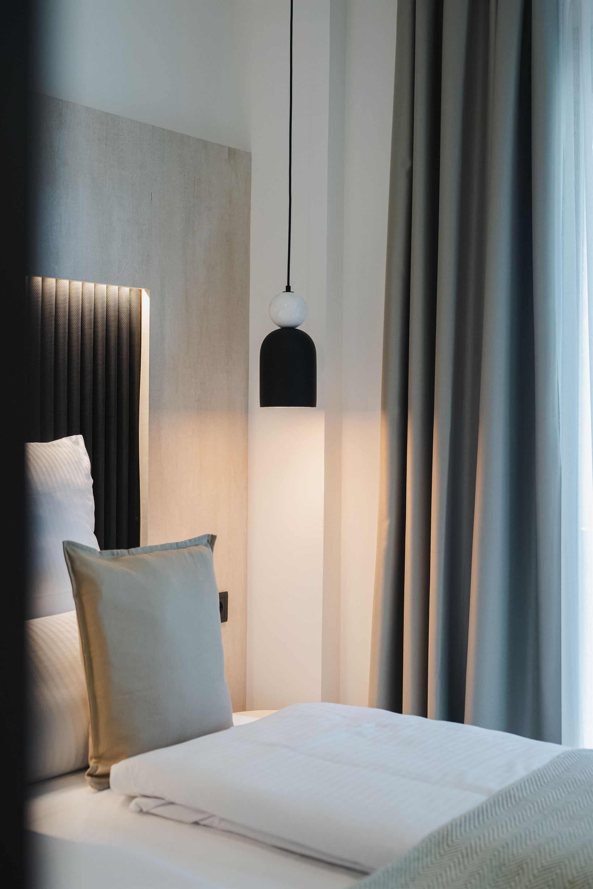 A bedroom with a bed , curtains , a lamp and a window.