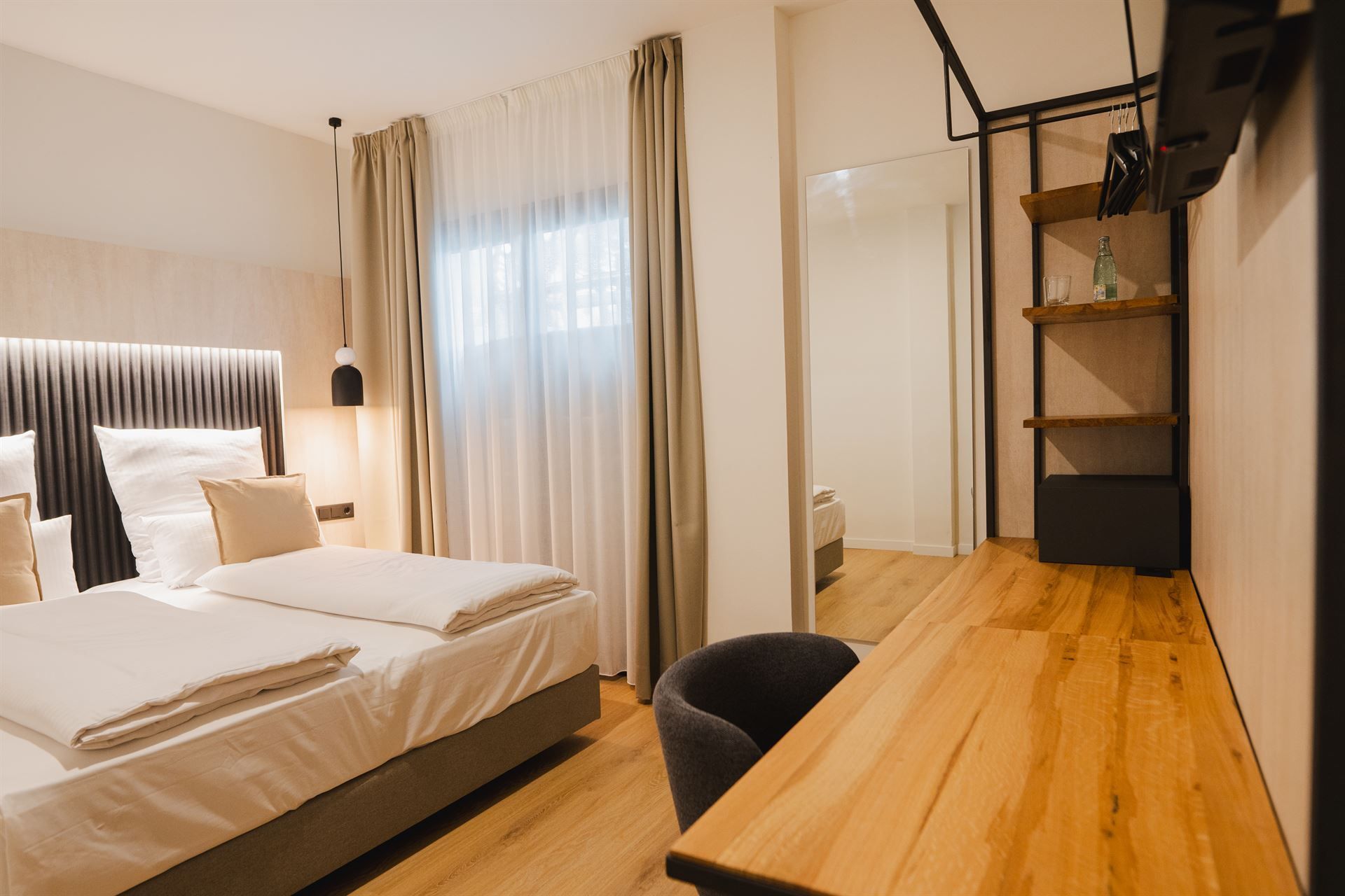 A hotel room with two beds and a wooden desk.