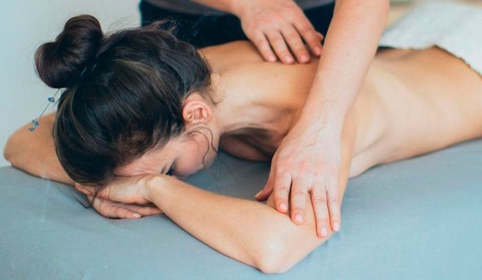 A woman is laying on a table getting a massage.