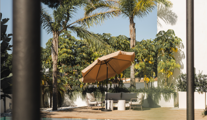 A large umbrella is sitting next to a swimming pool in a backyard.