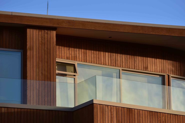 Cuisine blanche lumineuse avec électroménagers en acier inoxydable, grand îlot central, plancher en bois et porte vitrée donnant sur l'extérieur.