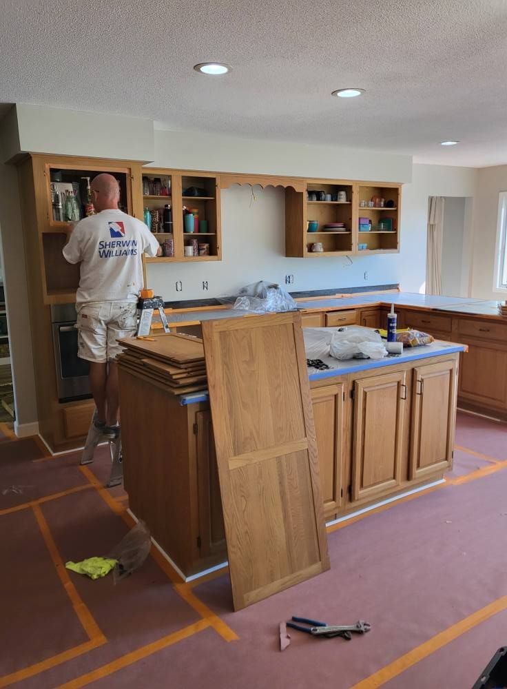 A man in a white shirt is working on a kitchen.