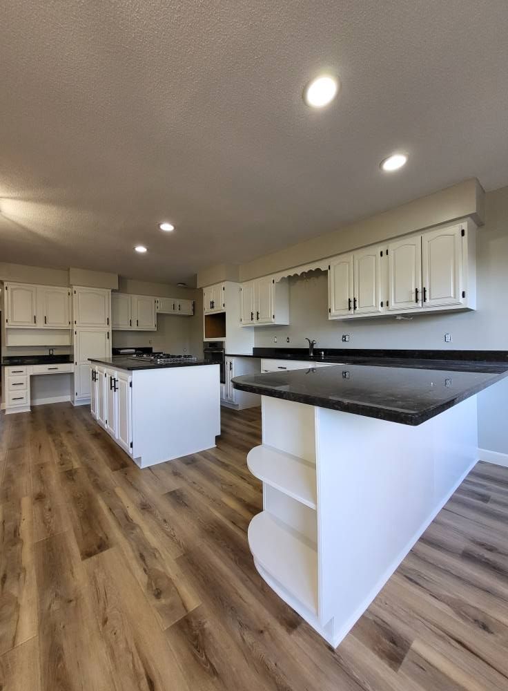 A kitchen with white cabinets and a black counter top