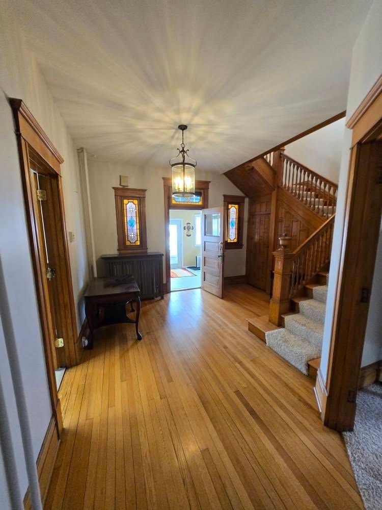 A hallway with wooden floors and stairs in a house.