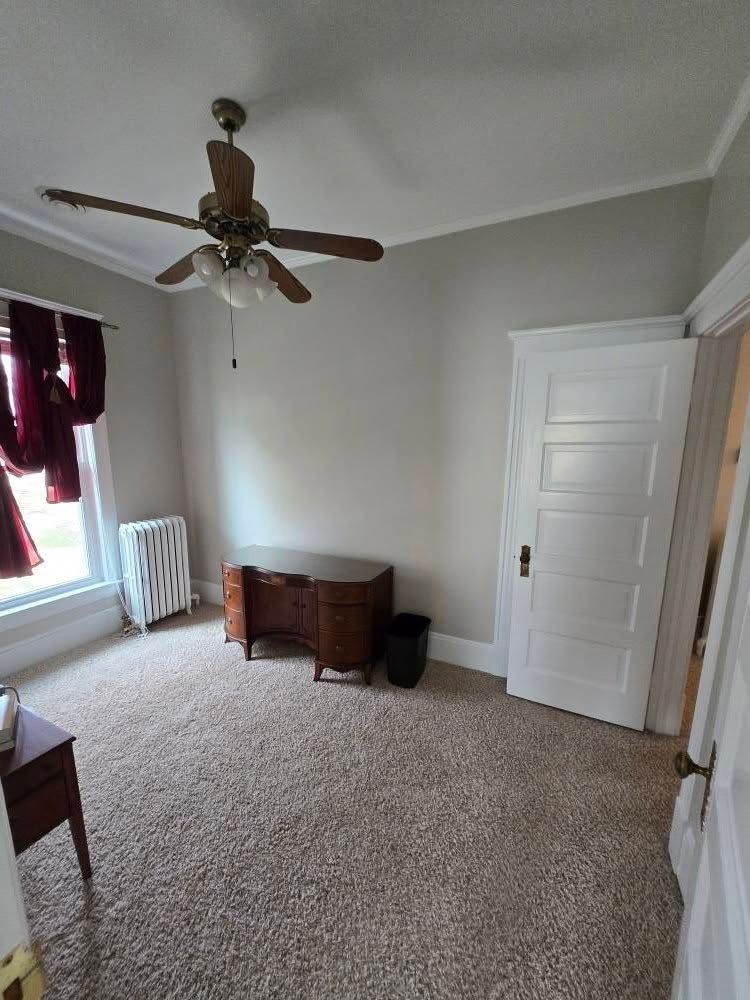 There is a ceiling fan in the room with a desk.