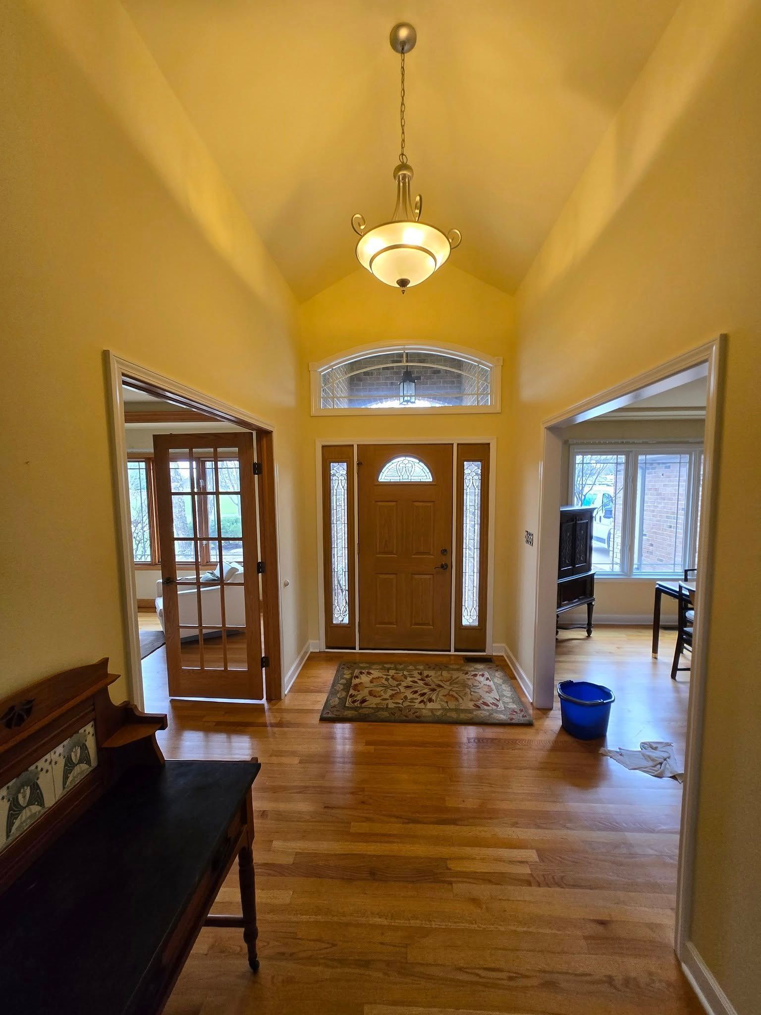 A hallway in a house with hardwood floors and a chandelier hanging from the ceiling.