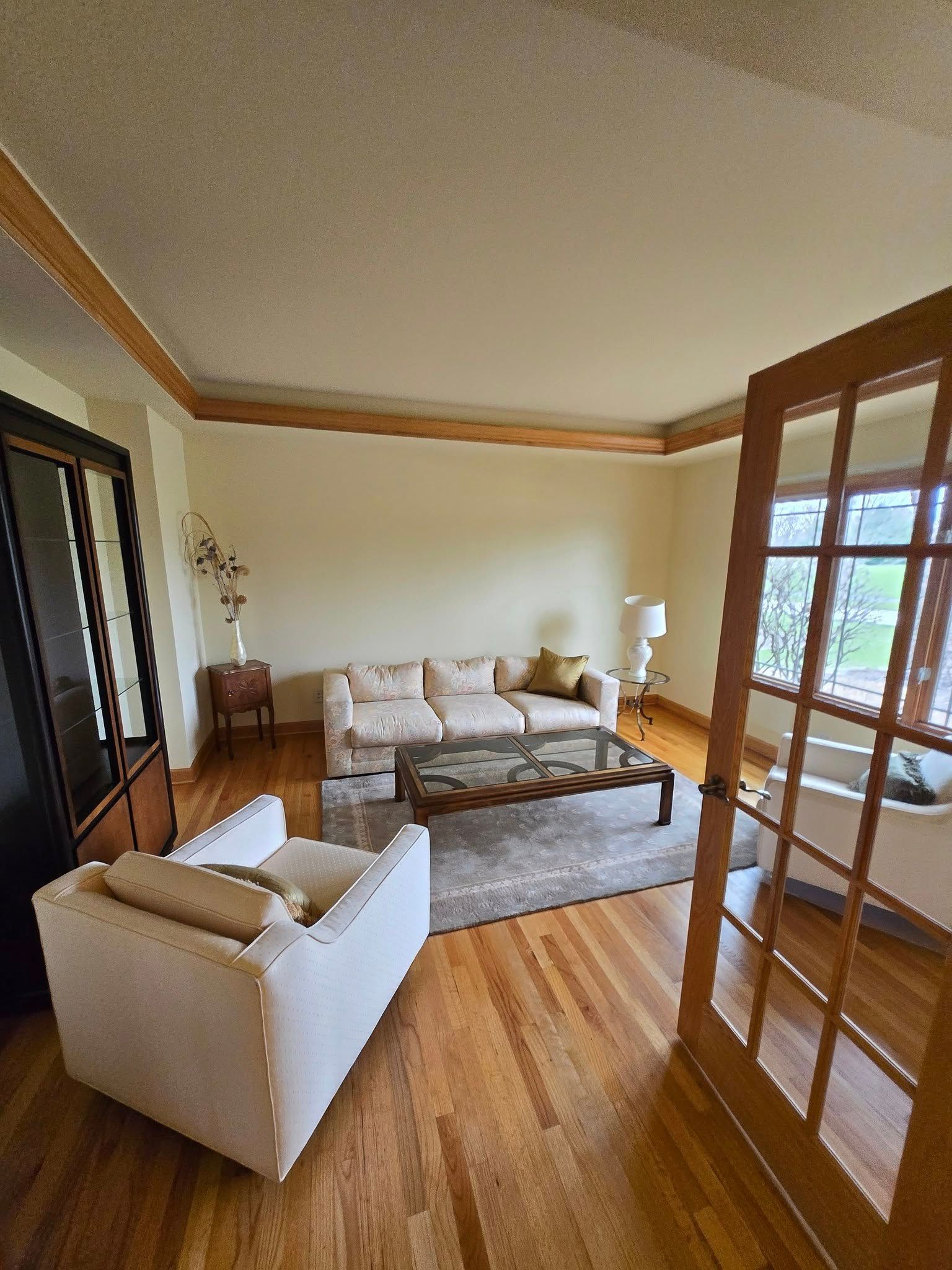 A living room with a couch , chair , coffee table and french doors.