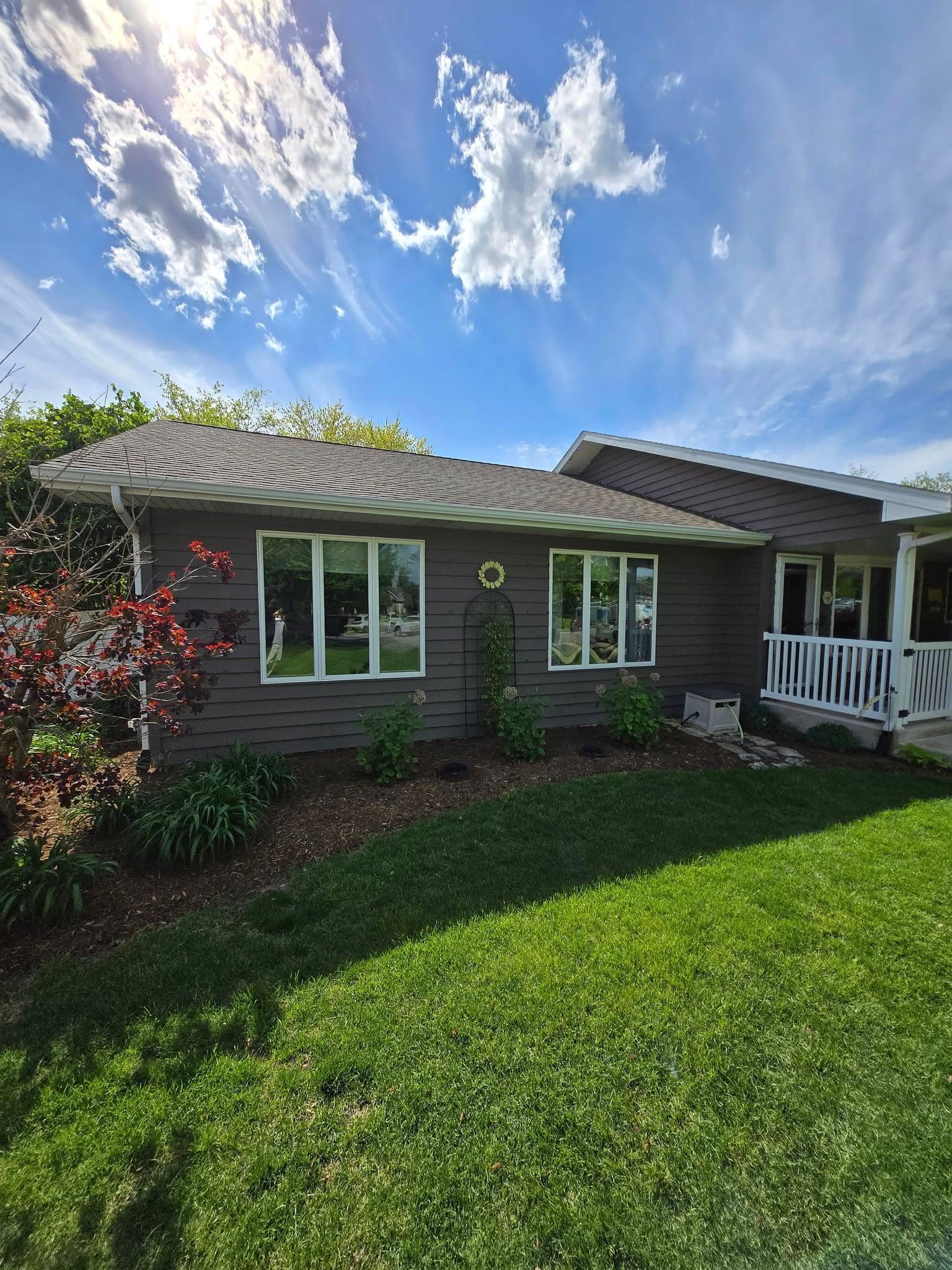 A house with a lot of windows and a large lawn in front of it.
