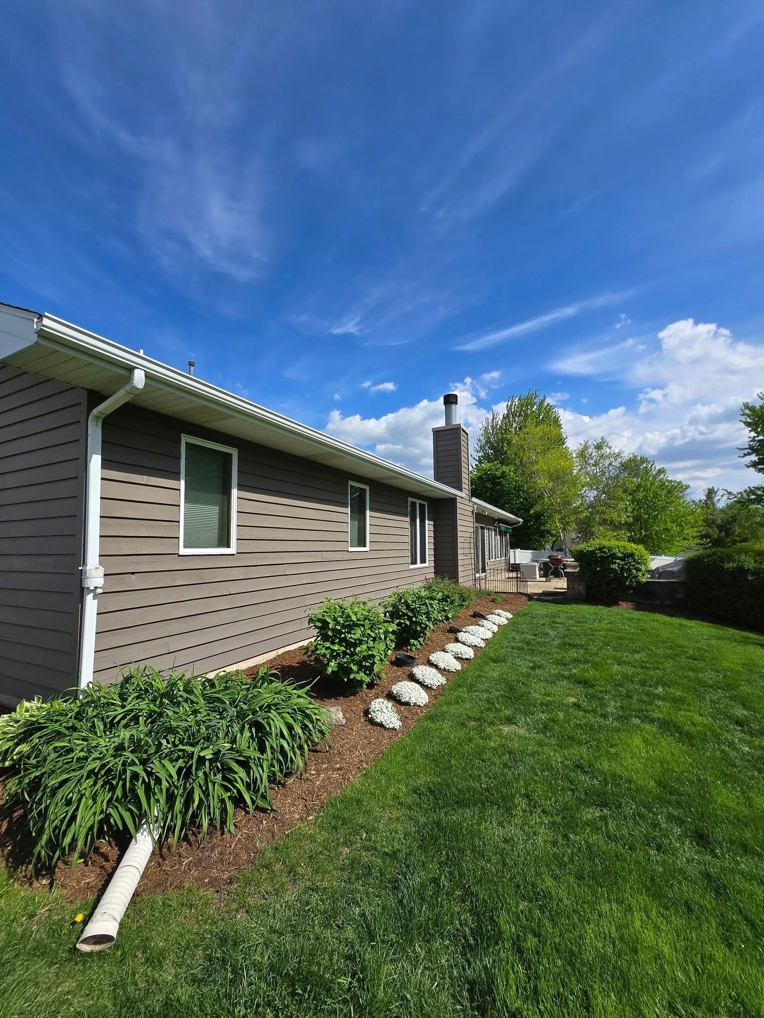 A house with a lush green lawn in front of it on a sunny day.