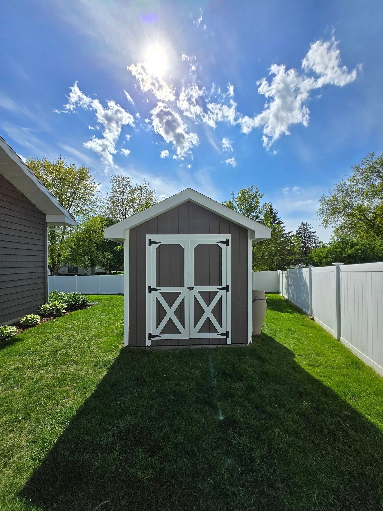 A shed is sitting in the middle of a lush green yard.