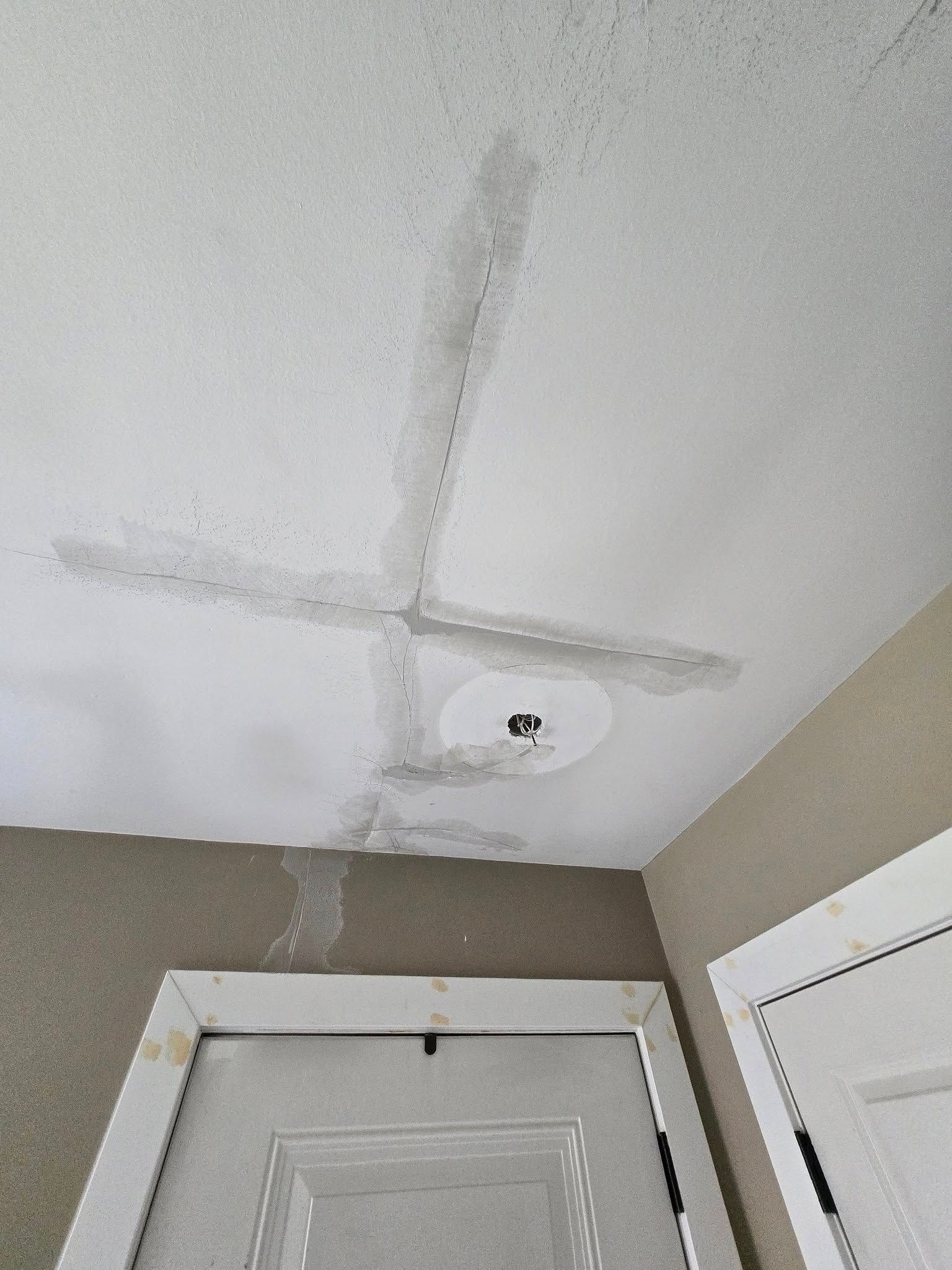 The ceiling of a room with a door and a ceiling fan.