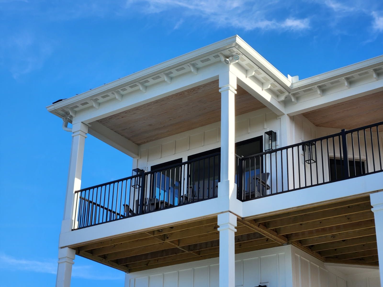 A white house with a balcony and a blue sky in the background