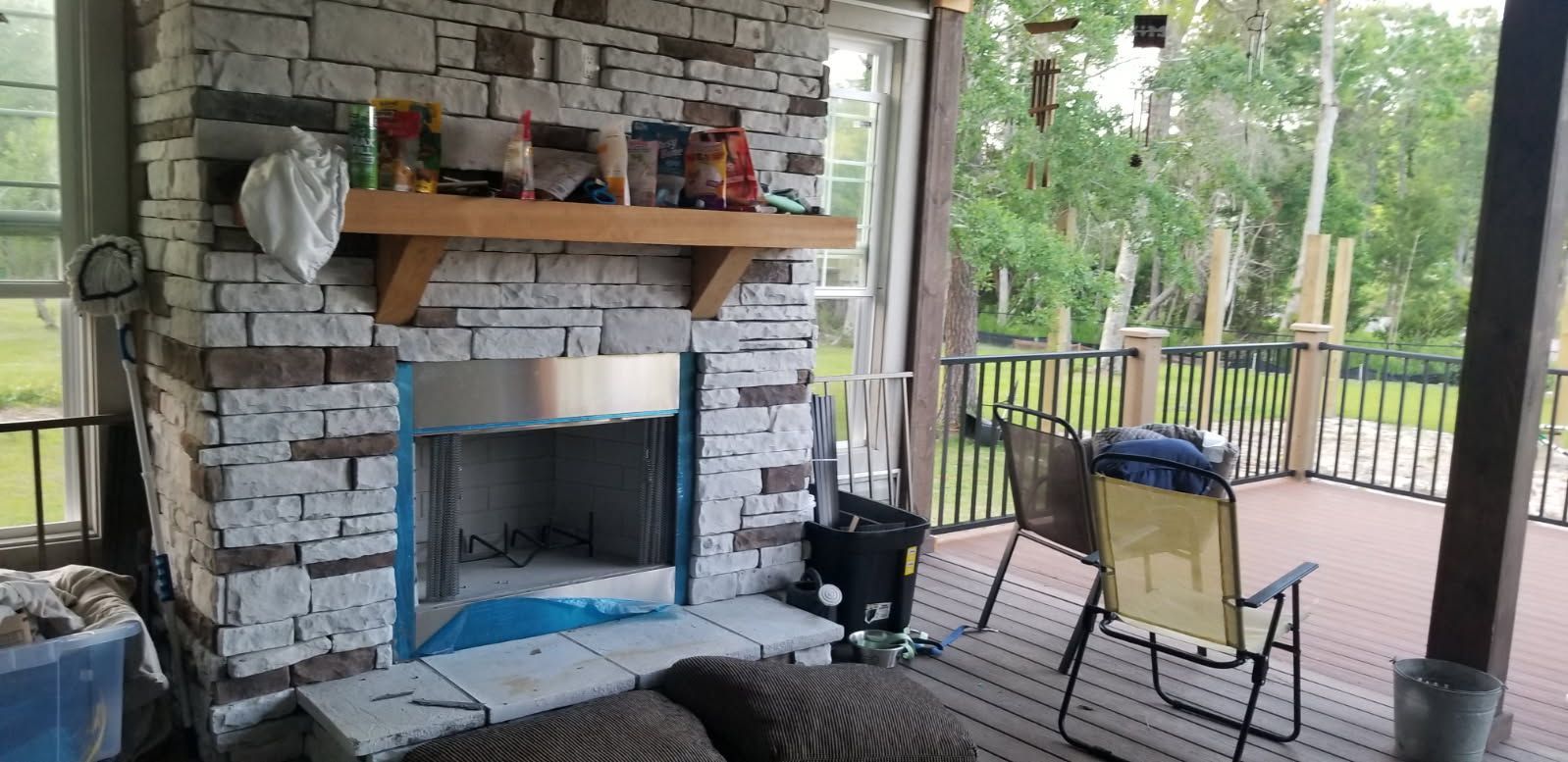 A brick fireplace is being built on a screened in porch.