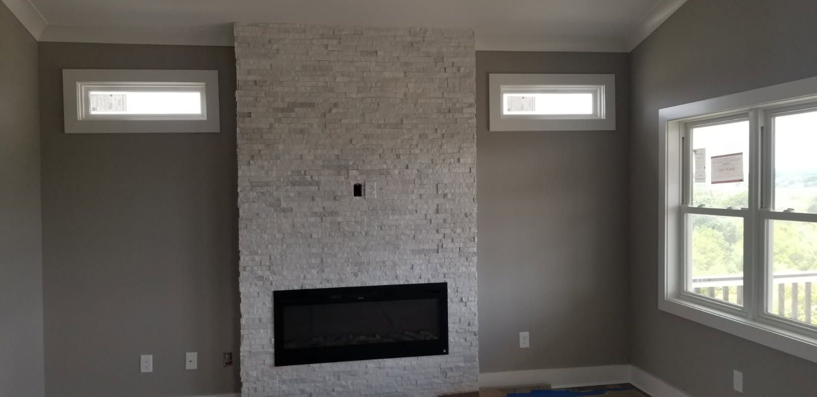 A living room with a fireplace and two windows.