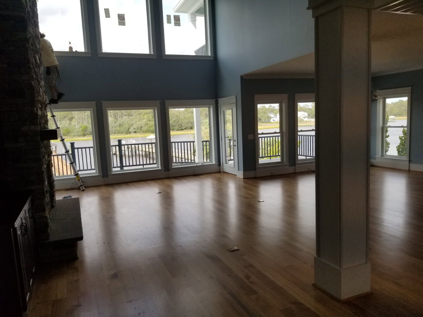 A large empty living room with hardwood floors and lots of windows.