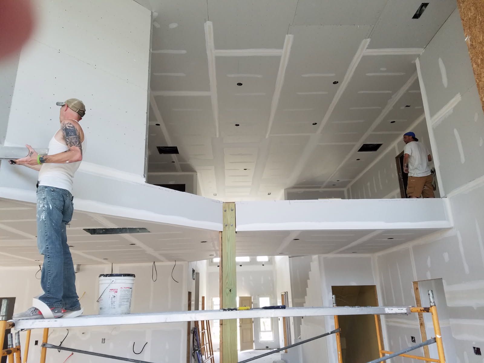 A man is standing on a scaffolding painting a wall.