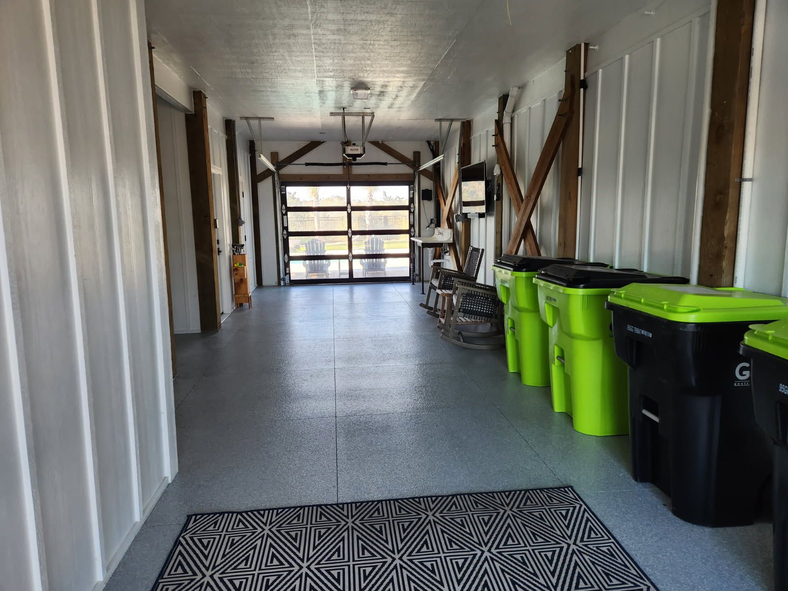 A hallway with green trash cans and black trash cans
