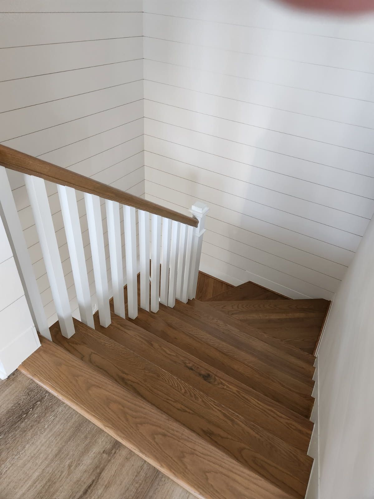 A wooden staircase with a white railing in a house.