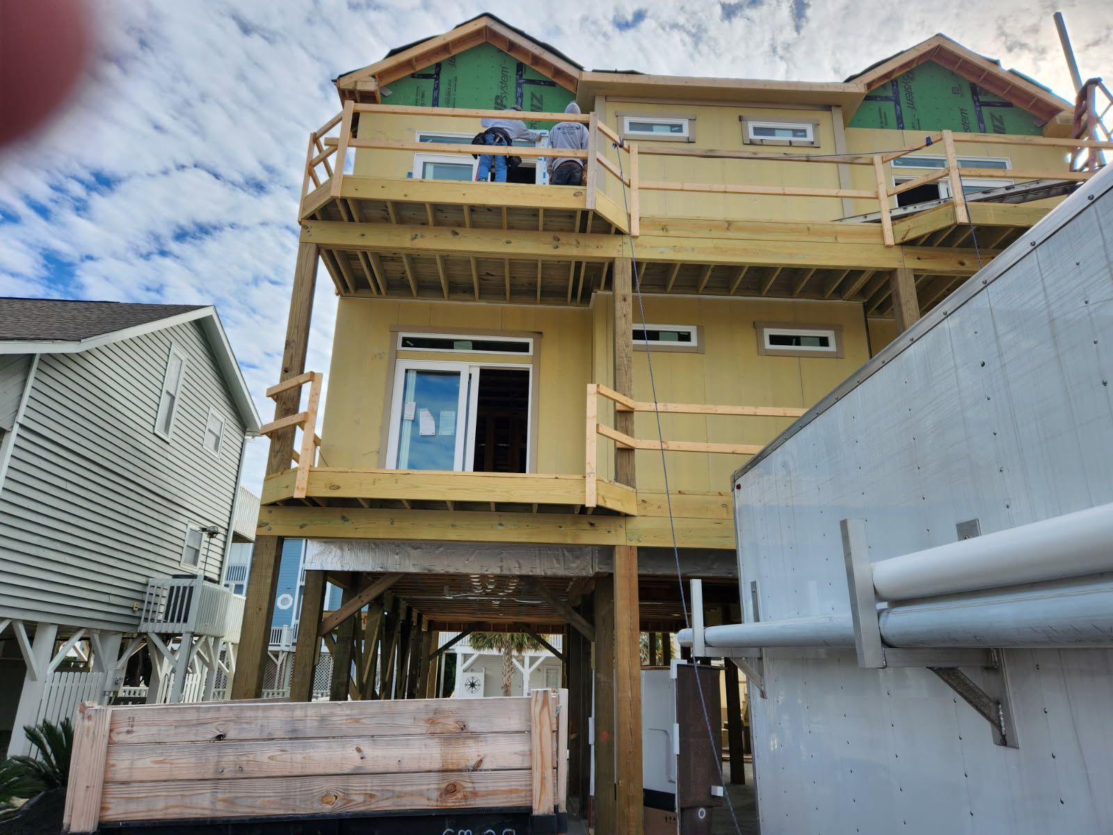 A house is being built on stilts and has a large deck.