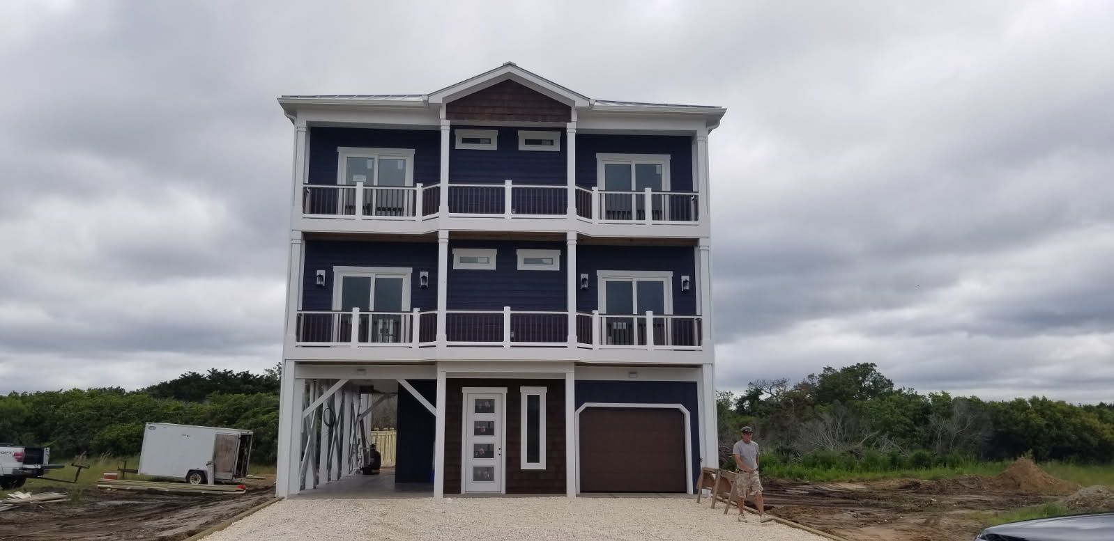 A large blue and white house is being built on a cloudy day.