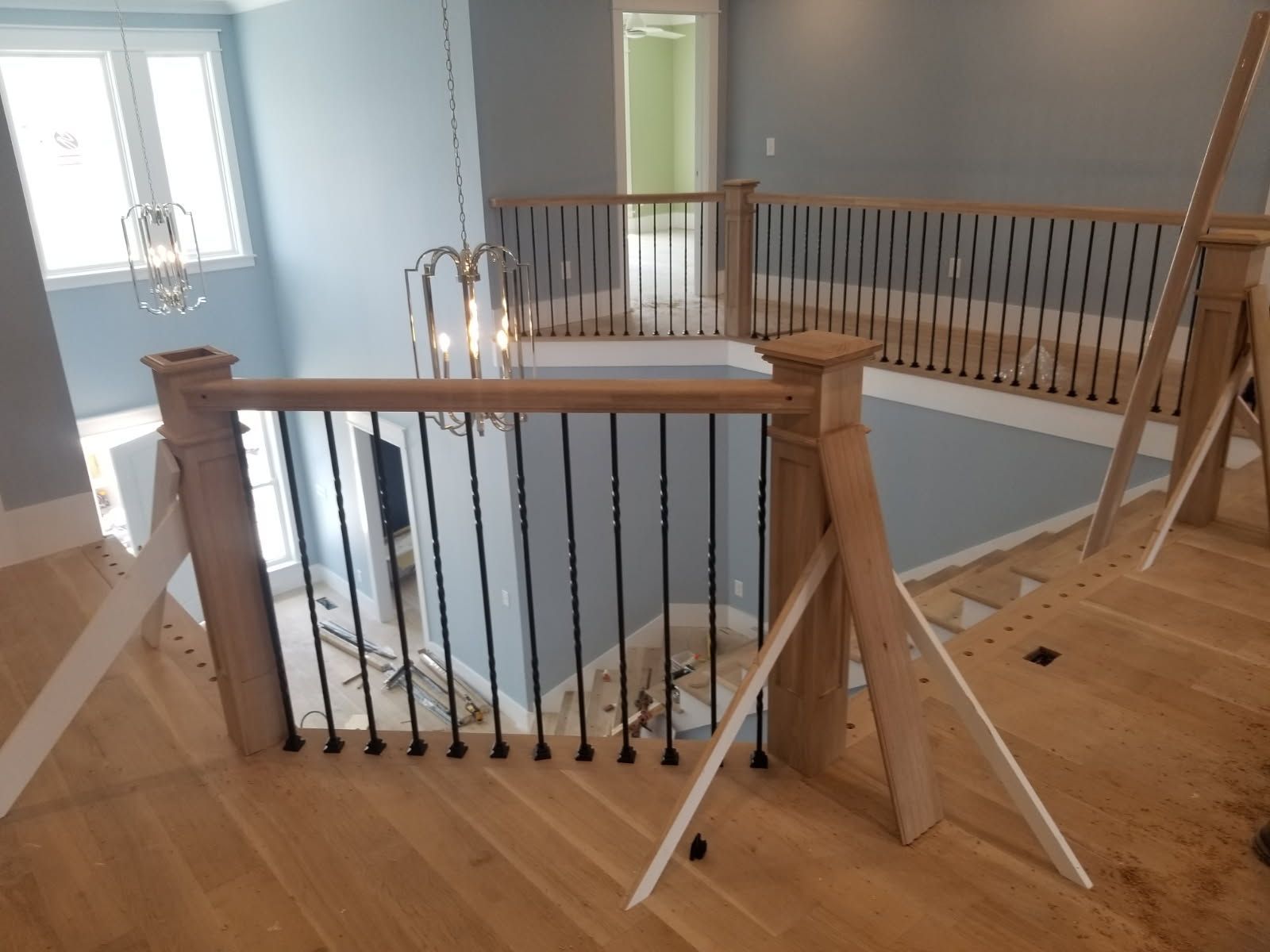 A wooden staircase with a wrought iron railing is being built in a house.