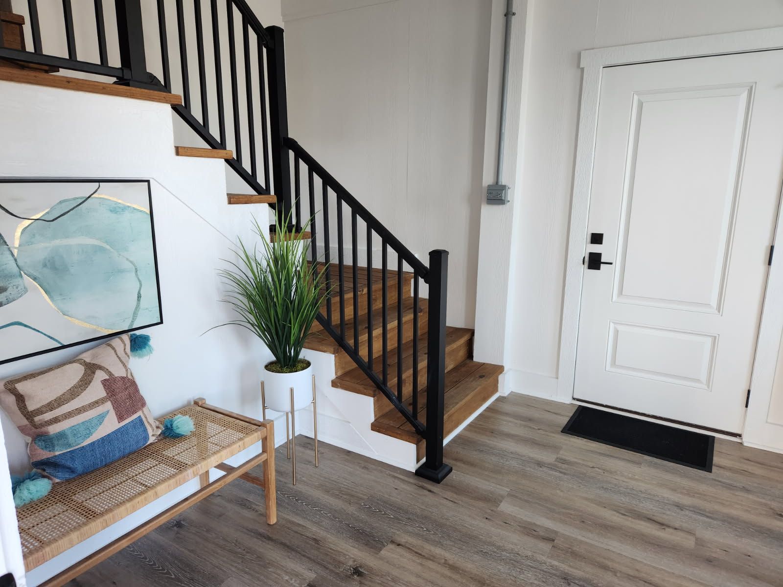 A hallway with stairs leading up to a white door.