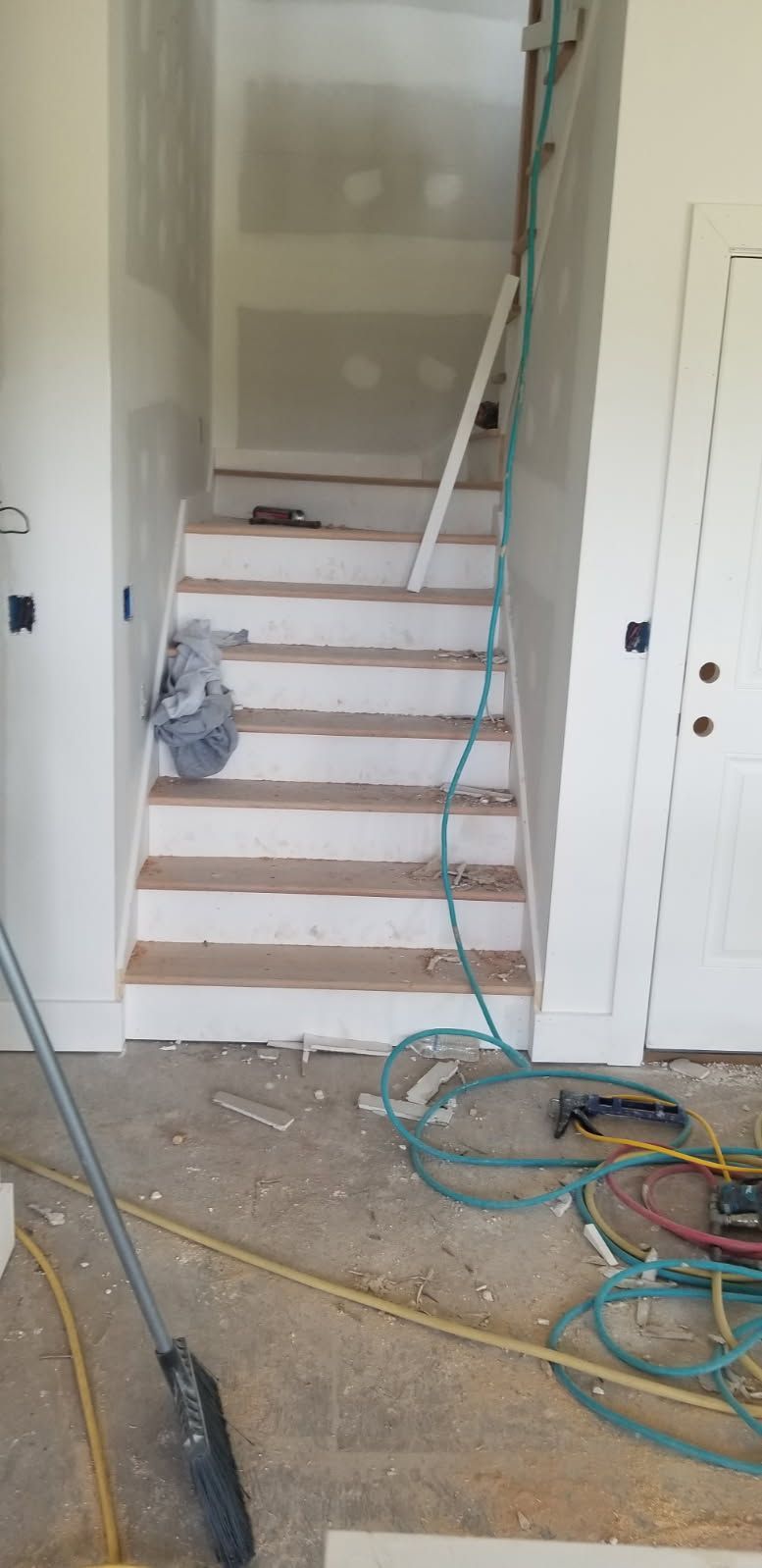 A hose is laying on the floor next to a staircase in a room.
