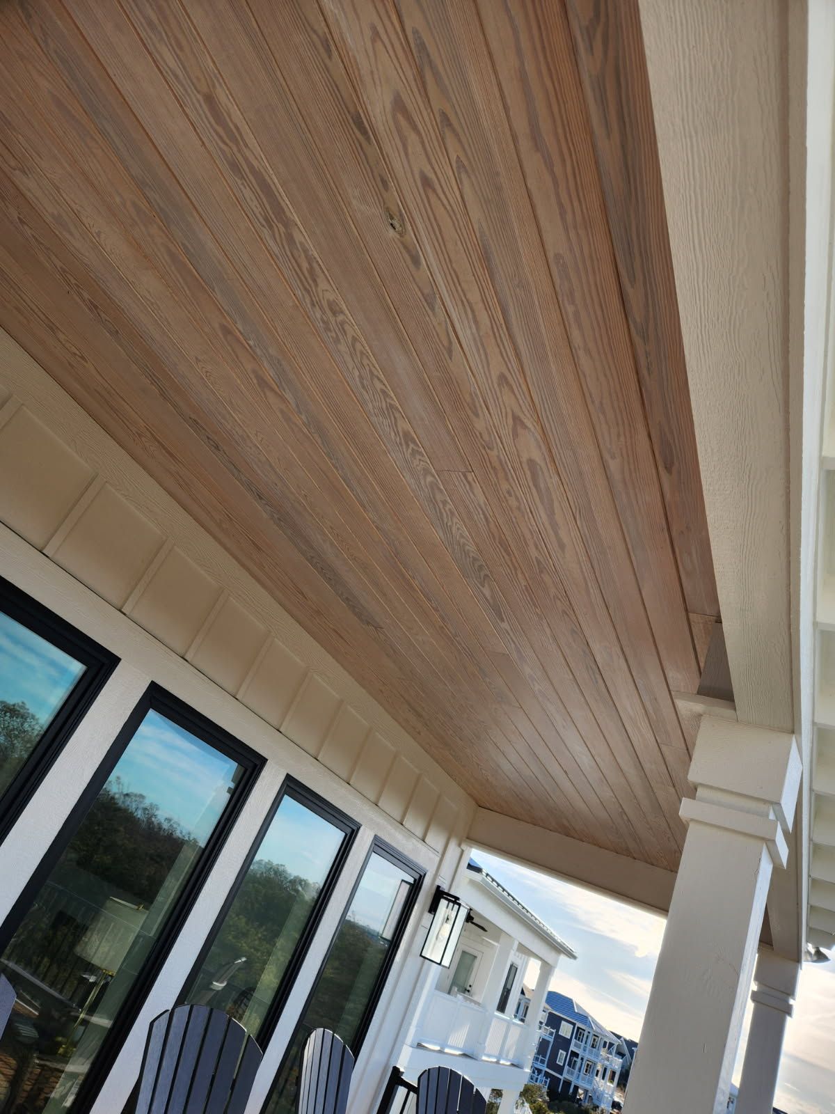 A porch with a wooden ceiling and a lot of windows.