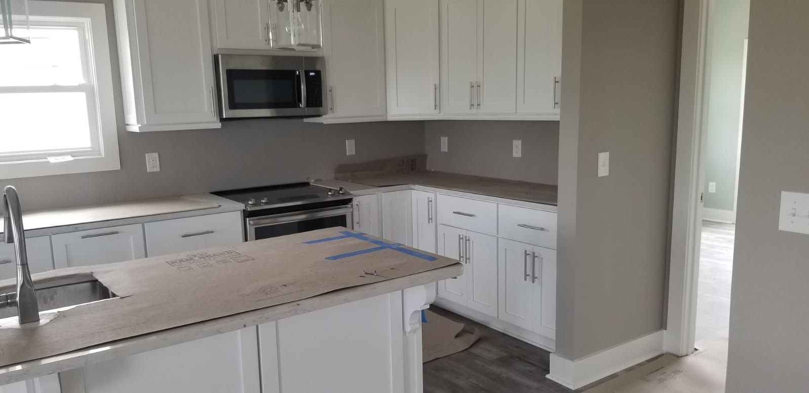 A kitchen with white cabinets , granite counter tops , stainless steel appliances , and a sink.