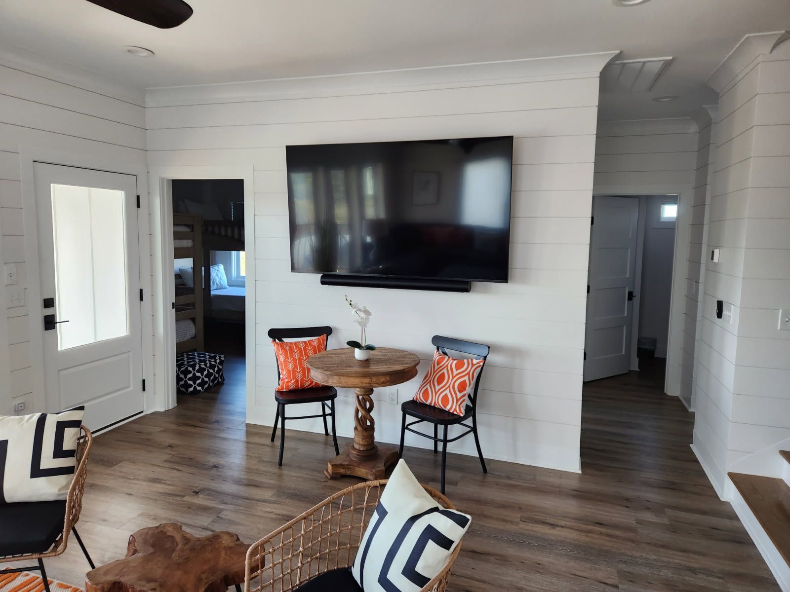 A living room with a table and chairs and a flat screen tv on the wall.