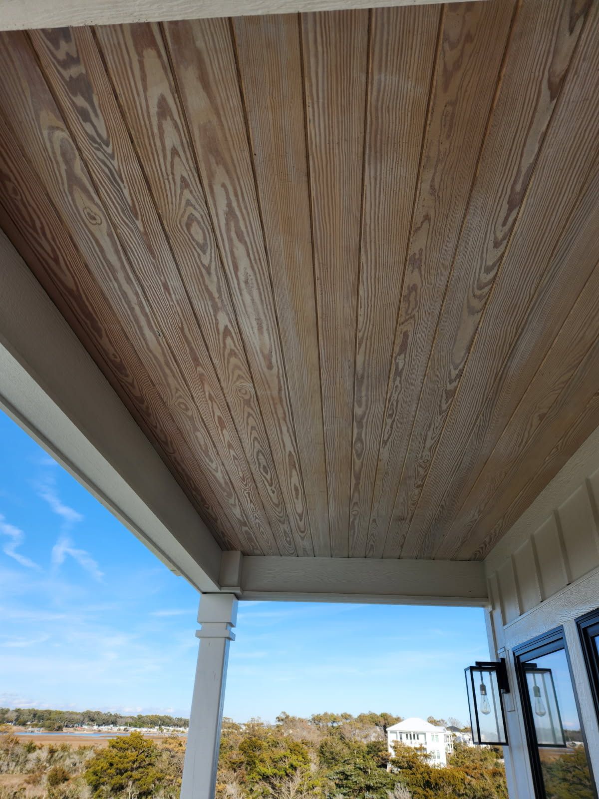 The ceiling of a porch with a view of the ocean.