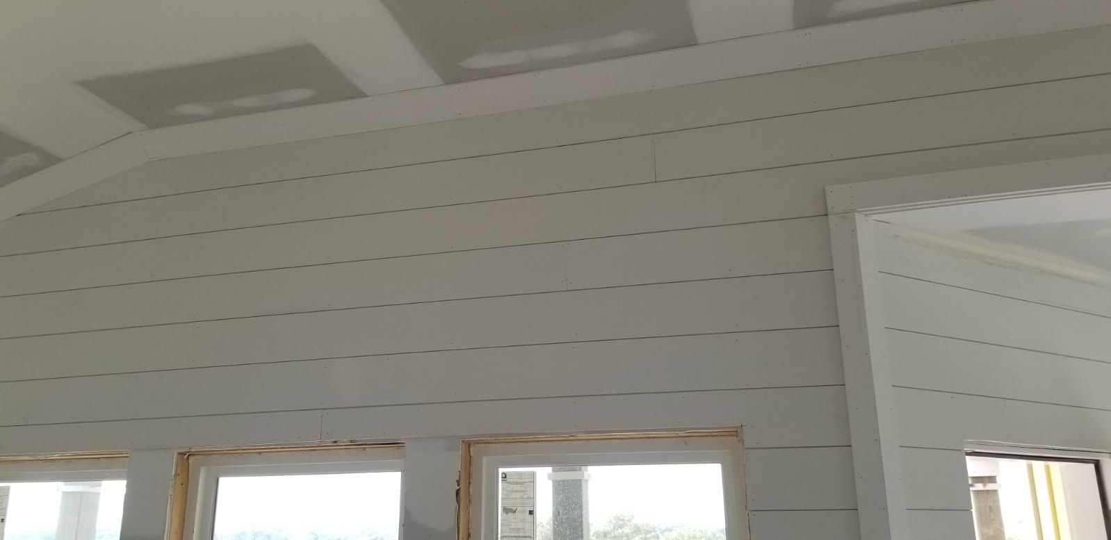 A room with a ceiling that is being built and a lot of windows.