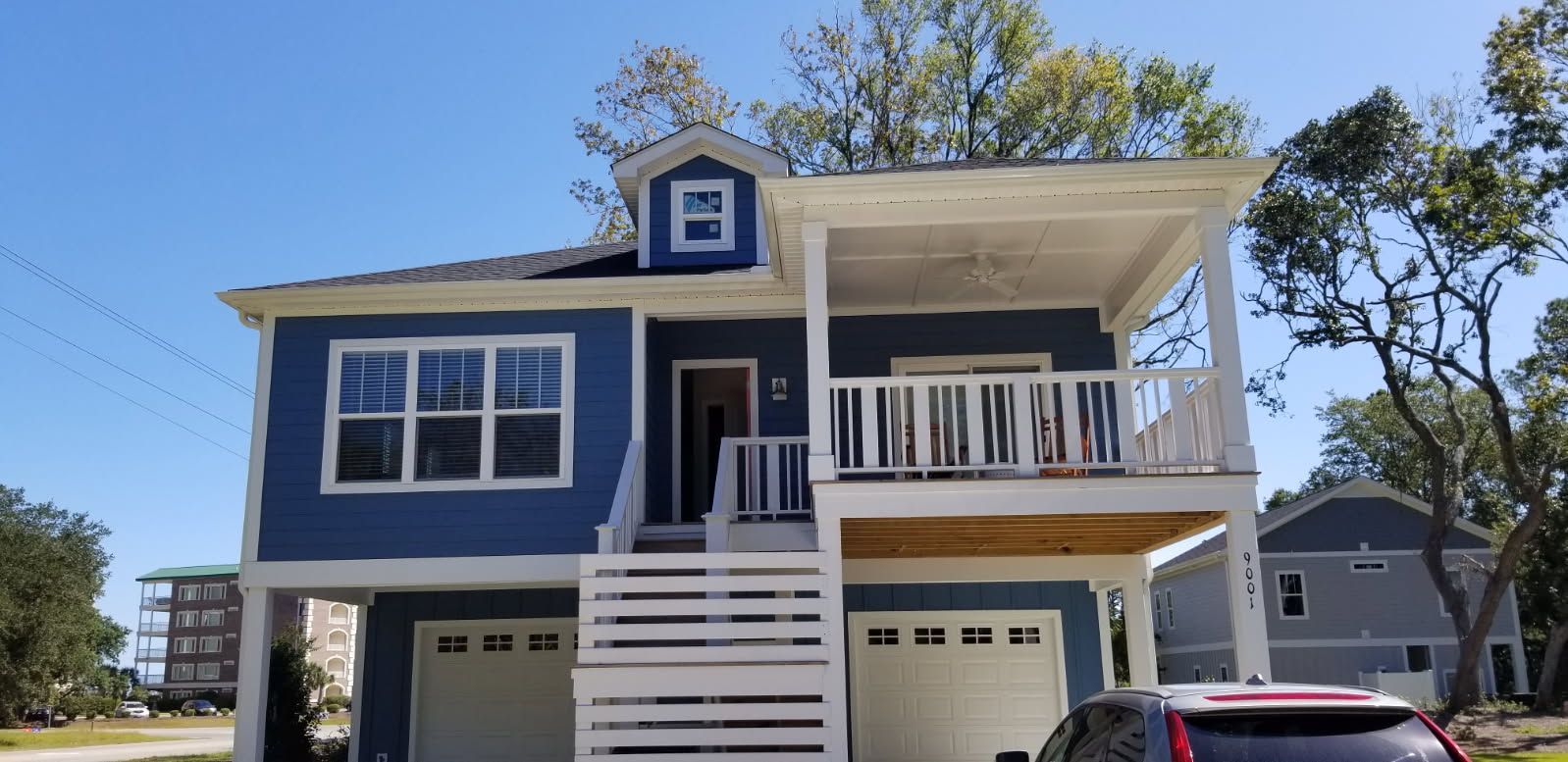 A blue and white house with a car parked in front of it.