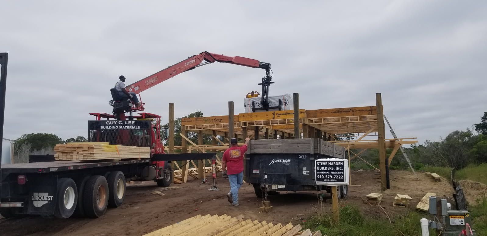 A man is standing next to a truck with a crane on it.