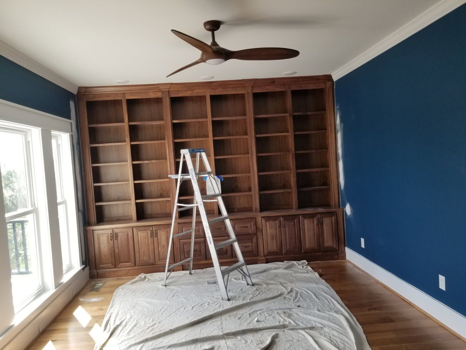 A room with a ladder in it and a ceiling fan