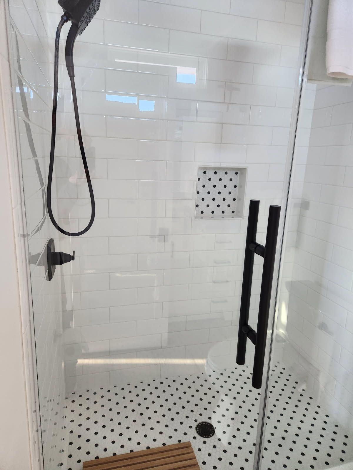 A shower with a black handle and a black shower head.