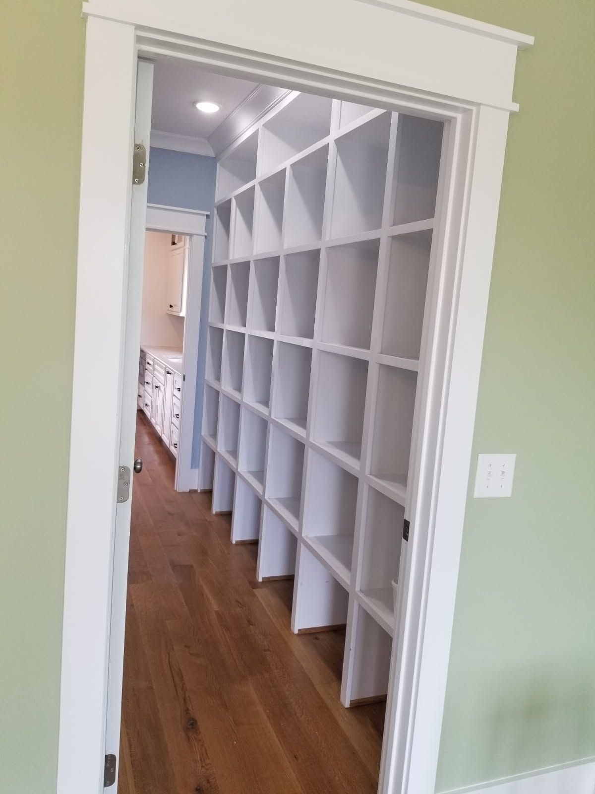 A walk in closet with lots of shelves and a wooden floor