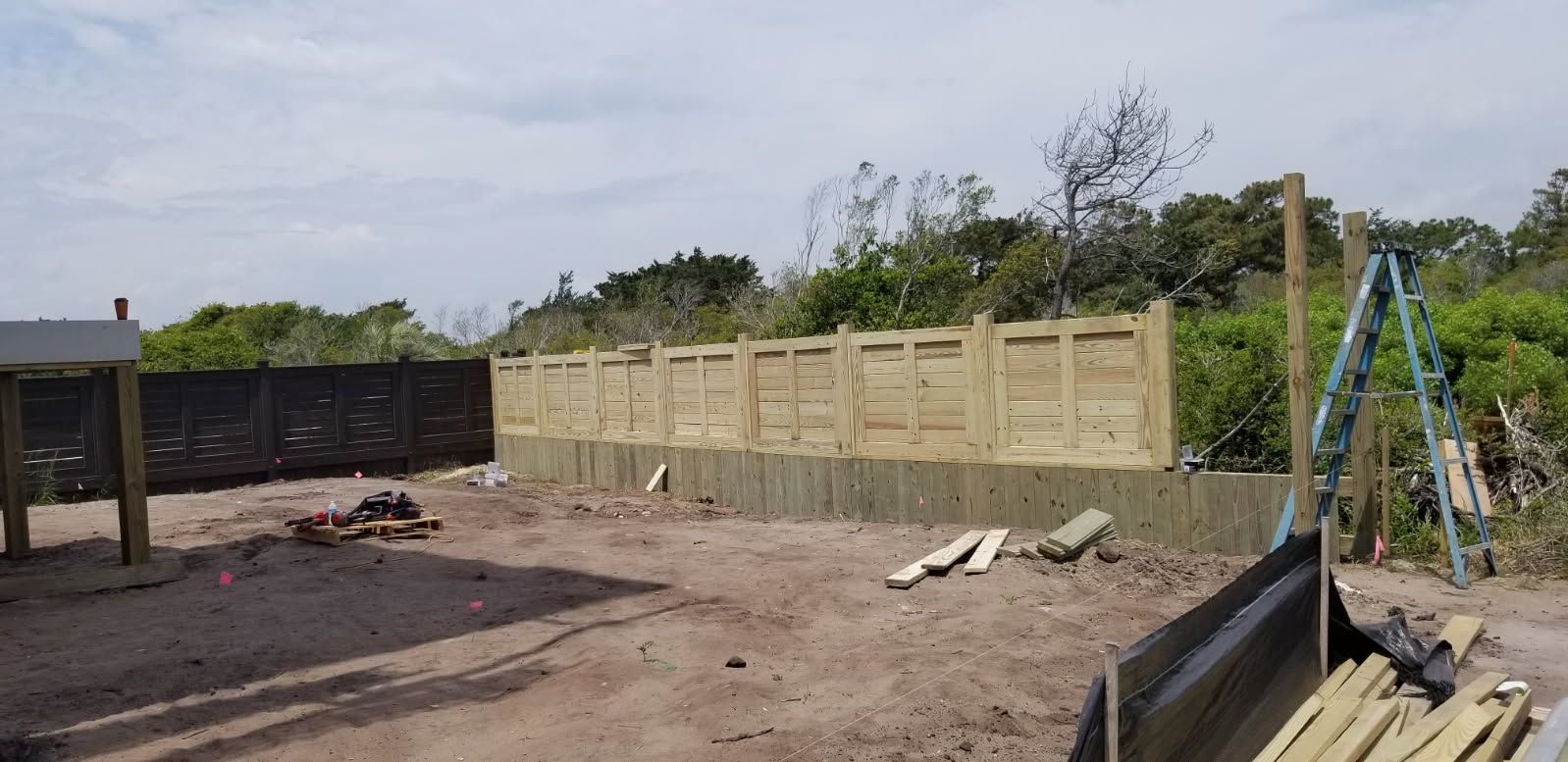 A wooden fence is being built in the backyard of a house.