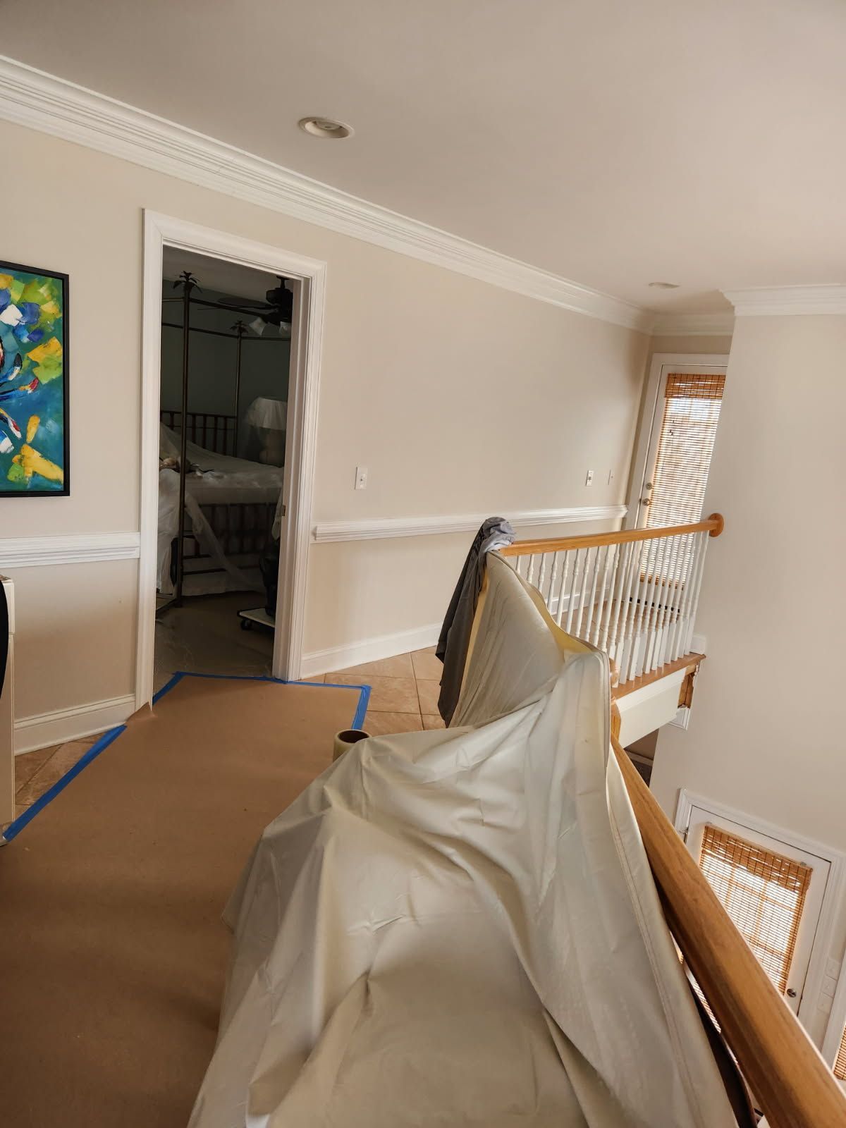 A room with a staircase and a painting on the wall.