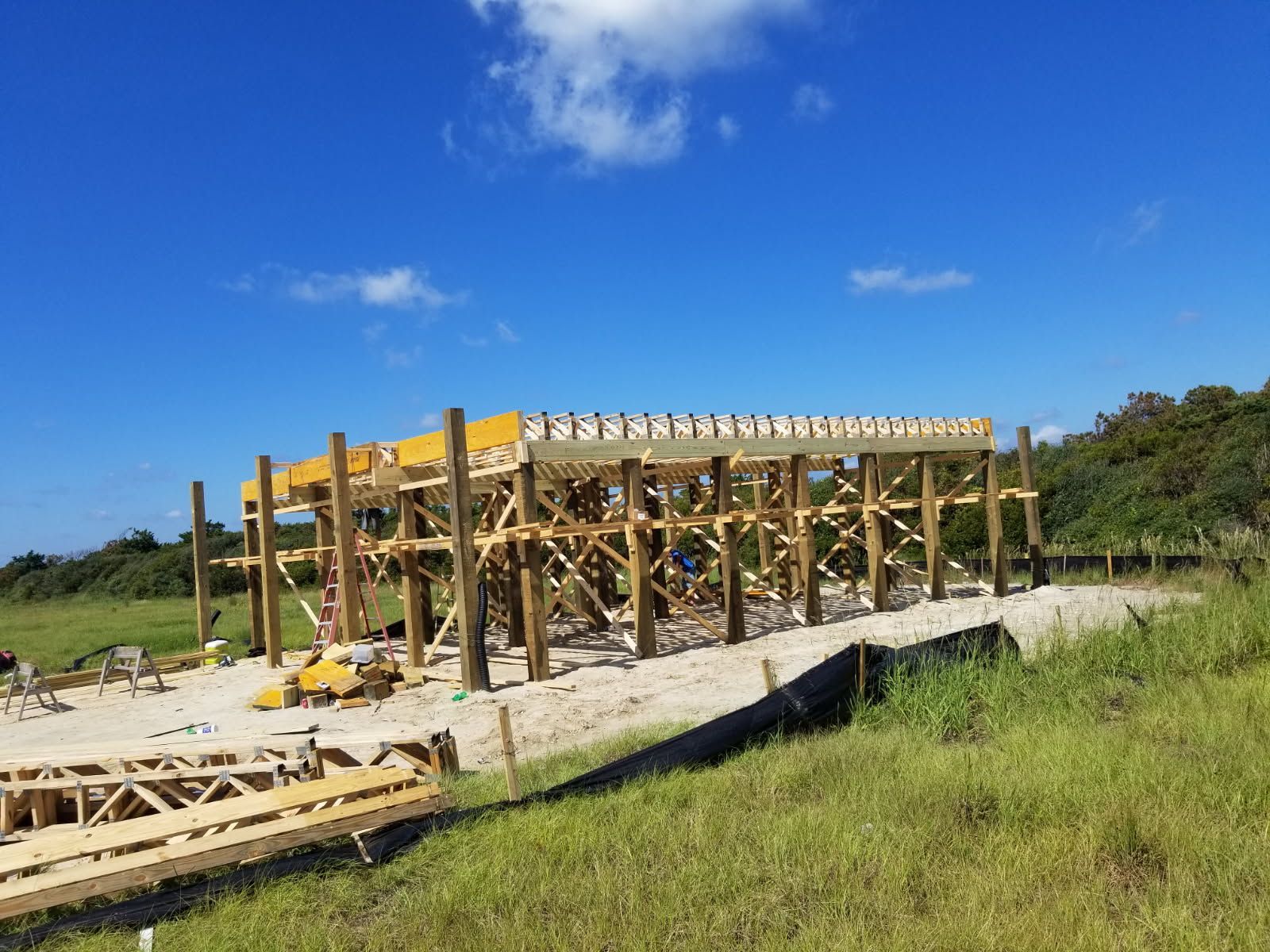 A large wooden structure is being built in a field.
