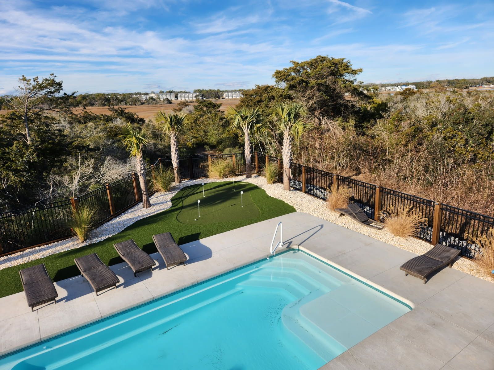 An aerial view of a large swimming pool surrounded by chairs and palm trees.