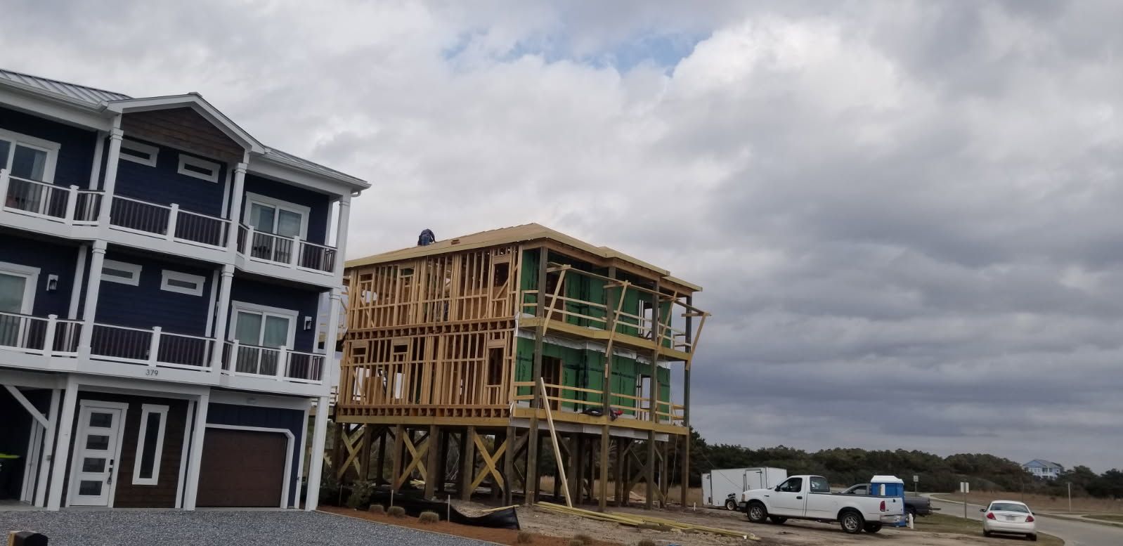 A group of houses are being built on stilts on a cloudy day.