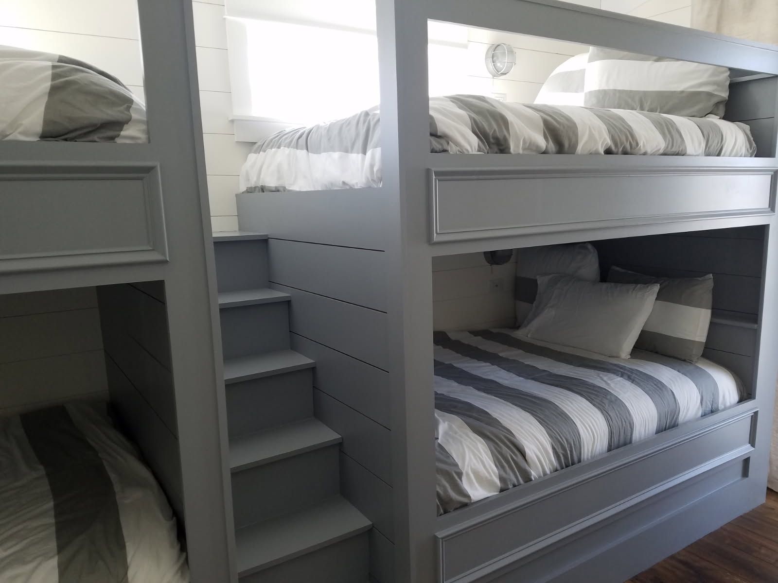A bunk bed with three beds and stairs in a room.