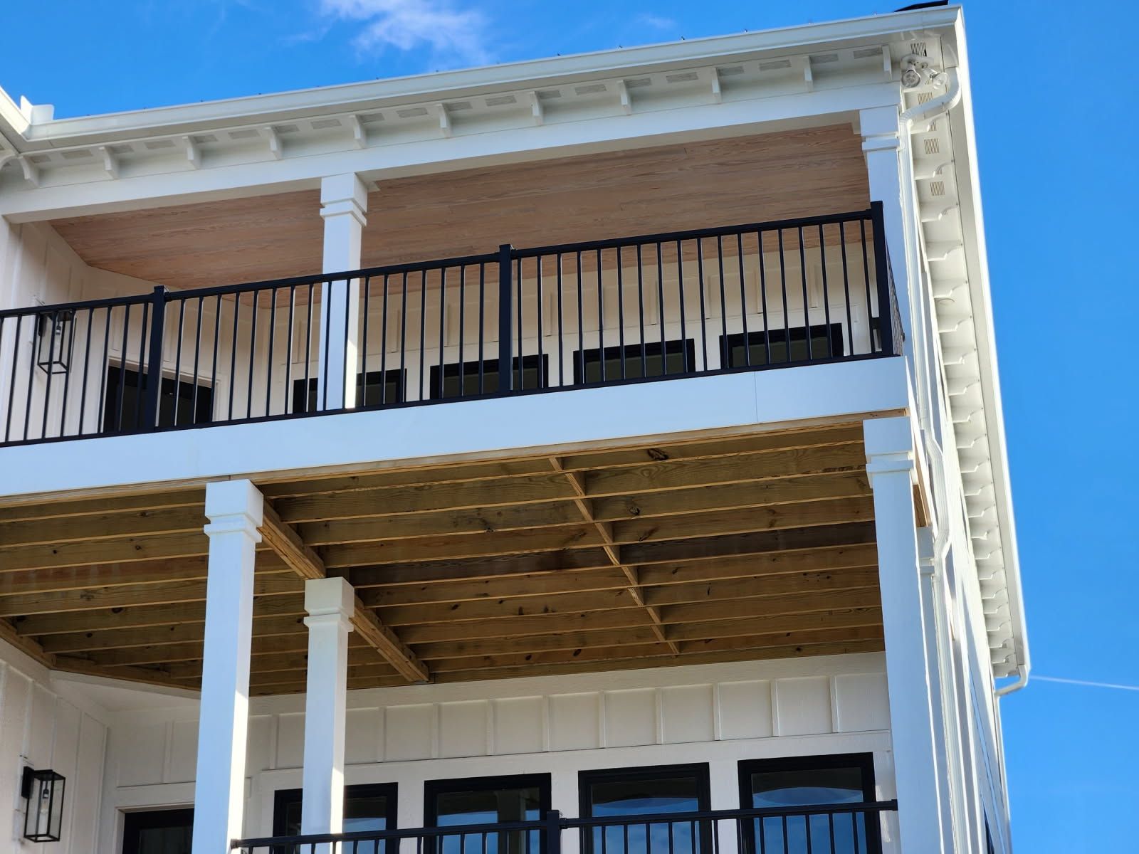 A white house with a balcony and a blue sky in the background
